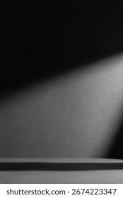 Dark dramatic background with sharp shadows and a beam of light. Minimalist abstract backdrop for creative design, concepts of mystery, contrast, solitude, or cinematic atmosphere.