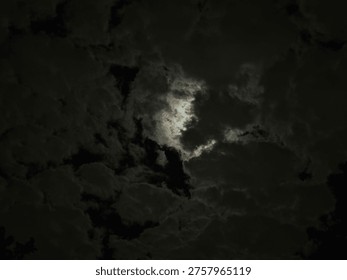 Dark dramatic clouds with light breaking through, creating a moody atmospheric sky. Symbolic of contrast, mystery, and changing weather.
