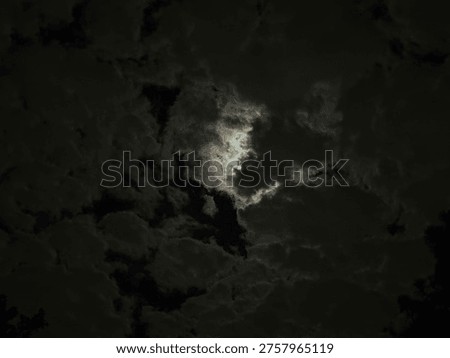 Dark dramatic clouds with light breaking through, creating a moody atmospheric sky. Symbolic of contrast, mystery, and changing weather.
