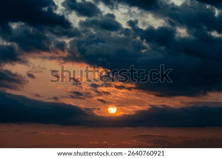 Dark dramatic horizon sky during sunset. Black clouds and setting sun. Evening sunshine background