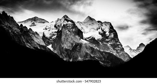 Dark dramatic mountain range with snow on peaks - Black and white monochrome - Powered by Shutterstock