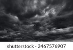 dark dramatic sky with black stormy clouds before rain or snow as abstract background, extreme weather, the sun shines through the clouds, high contrast photo