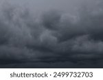 dark dramatic sky with black stormy clouds before rain or snow as abstract background, extreme weather, the sun shines through the clouds, high contrast photo
