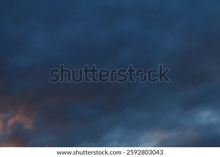 dark dramatic sky with black stormy clouds before rain or snow as abstract background, extreme weather, the sun shines through the clouds, high contrast photo
