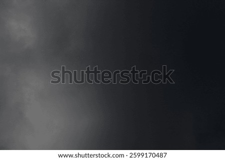 dark dramatic sky with black stormy clouds before rain or snow as abstract background, extreme weather, the sun shines through the clouds, high contrast photo 
