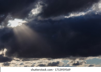 dark, dramatic sky, rain clouds, sun rays breaking through black clouds, close-up with blurred background