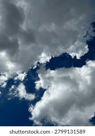 Dark and dramatic storm clouds covering the sky with patches of blue visible through the cloud formations. A powerful atmospheric weather scene symbolizing change, uncertainty, hope, climate conditions, and natural beauty.
