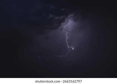 Dark, dramatic storm clouds gather on the horizon, hinting at an approaching thunderstorm. The sky is a canvas of intense grays and deep blues, with a powerful sense of impending weather. This image c
