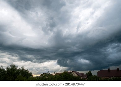 Dark dramatic storm clouds gathering over a rural landscape before a thunderstorm. Moody sky with swirling cloud formations, severe weather, approaching rain and powerful atmospheric conditions.