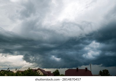 Dark dramatic storm clouds gathering over a rural landscape before a thunderstorm. Moody sky with swirling cloud formations, severe weather, approaching rain and powerful atmospheric conditions.