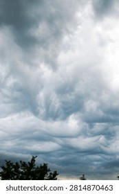 Dark dramatic storm clouds gathering over a rural landscape before a thunderstorm. Moody sky with swirling cloud formations, severe weather, approaching rain and powerful atmospheric conditions.