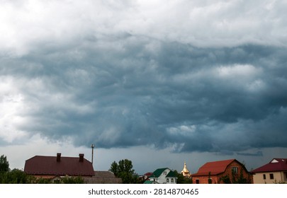 Dark dramatic storm clouds gathering over a rural landscape before a thunderstorm. Moody sky with swirling cloud formations, severe weather, approaching rain and powerful atmospheric conditions.