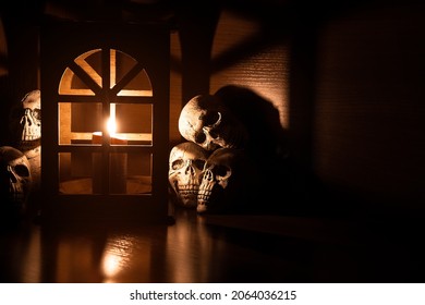 Dark Dungeon Decoration Table Of Vintage Lantern Candle Light And Human Skulls In Shadow Environment With Copy Space, Soft Focus Concept  