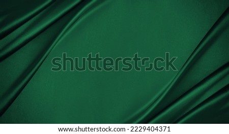 Dark emerald green silk satin. Smooth silky fabric. Luxury background with space for design. Flat lay, top view table. Christmas.