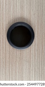 The dark, empty circular space in the center contrasts with the textured wood background, creating a minimalistic composition ideal for interior design or workspace themes.