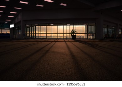 Dark empty hall interior with floor to ceiling windows and scenic background. Empty seats in the departure lounge at the airport