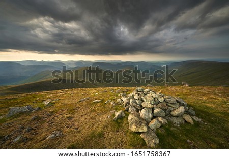 Dark evening clouds in the mountains before sunset from the summit of Rampsgill Head with Rest Dodd, The Nab and Martindale Common in the distance with Ramps Gill far below in the Lake District