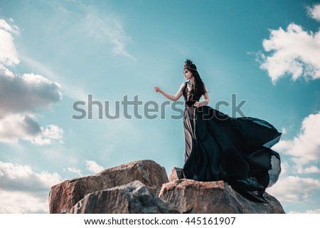 dark evil queen sneaks through the stone canyon, wild Princess , vampire , hip toning , creative color,dark boho. Woman in vintage long dress, train fluttering in the wind, flying, waving