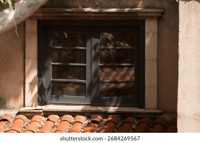 Dark framed window with soft reflections above terracotta tiles in Tlaquepaque, Sedona. A detail capturing authentic Mexican-inspired architecture.
