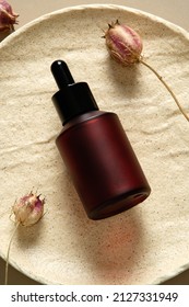 Dark Glass Dropper Cosmetic Bottle With Dried Flowers On Stone Plate Top View. Body Lotion Packaging Design, Luxury Style.