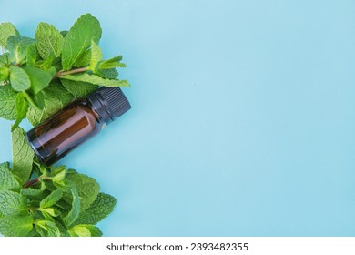 Dark glass essential oil bottle with bunch of peppermint on the light blue background. Mint essential oil for cold inhalation, place for text, copyspace. Alternative medicine, spa, relaxation - Powered by Shutterstock