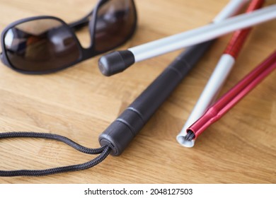 Dark glasses and sticks for blind on table closeup