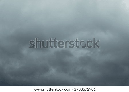 Dark gray clouds fill the frame. Thick storm clouds create a heavy atmosphere. Unbroken sunlight shows impending weather. Ideal for weather forecasts or dramatic backgrounds