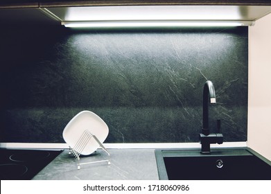 Dark Gray Laminate Worktop With Black Faux Stone Sink With Faucet In A Modern Kitchen.