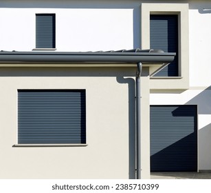Dark gray security rolling shutters on a facade of a new built house.