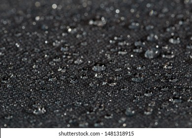 dark gray waterproof hydrophobic flat cloth closeup with rain drops selective focus background