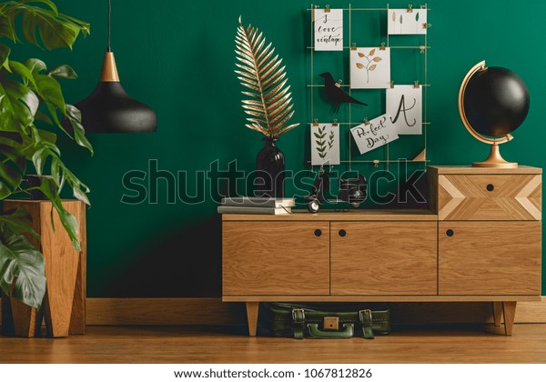 Dark green\
apartment interior with scandinavian style wooden furniture and\
designer black and gold\
decorations