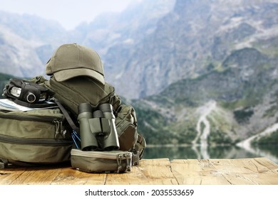 Dark green backpack on wooden desk and free space for your decoration. Blurred landscape of mountains. 
