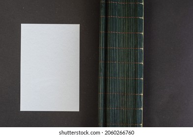 Dark Green Bamboo Table Cloth And White Rectangle Opposite Black Background. Plastic Blank Textured Card. Selective Focus.