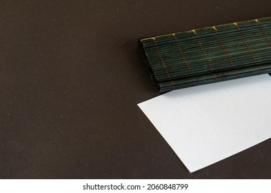 Dark Green Bamboo Table Cloth And White Rectangle Opposite Black Background. Plastic Blank Textured Card. Selective Focus.