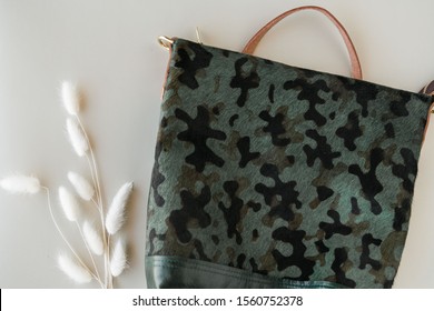 Dark Green Camo Backpack On Green Background With Dried Flowers