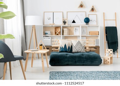 Dark Green Futon Couch With Decorative Pillows Standing In Scandi Living Room Interior With Simple Gallery, White Rack And Books