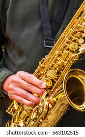 The Dark Green T Shirt Man's Hand With Golden Shiny Alto Saxophone With Strap.