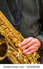 The Dark Green T Shirt Man's Hand With Golden Shiny Alto Saxophone With Strap.