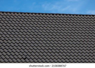 Dark grey or black brick rooftop under blue sky and white cloud, Tiles background details, Shingles texture, Abstract geometric pattern, Roof brick material.