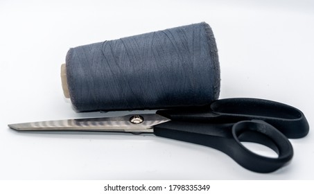Dark grey bobbin thread and black scissors isolated on white background. Close up of a spool of grey sewing thread. Thread is a type of yarn but similarly used for sewing. Side view. - Shutterstock ID 1798335349