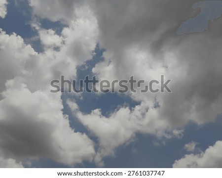 Dark and grey cumulative clouds float in the sunny daylight