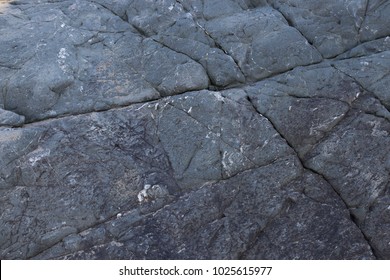 Dark Grey Rock Texure Background With Criss-crossing Cracks.