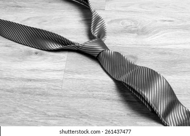 Dark grey tie on the floor in black and white