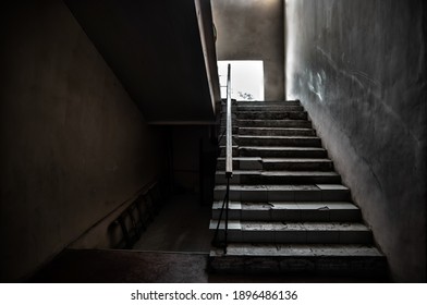 Dark grungy staircase with bright window in abandoned home. Inside old school