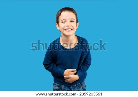 Dark haired little child over isolated blue background smiling and laughing hard out loud because funny crazy joke. Happy expression