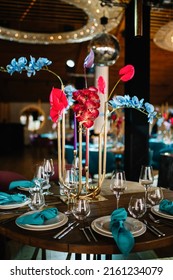 in the dark hall there are festive tables and chairs, tables decorated with compositions of flowers, greenery and candles. On the tables are glasses, plates and cutlery - Shutterstock ID 2161234079