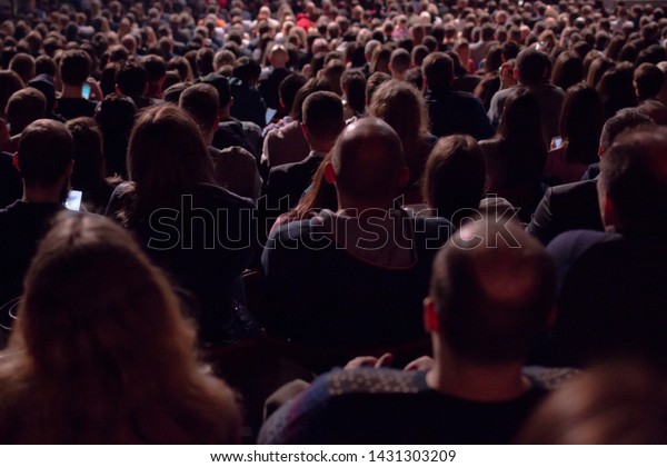 暗いホールでは 何百人もの人々が座って映画館でスクリーンを見たり 舞台で演じたりしている様子が見えます の写真素材 今すぐ編集
