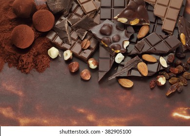 Dark Hazelnut And Almond Chocolate Bar Pieces And Truffles On Cocoa Powder   Background