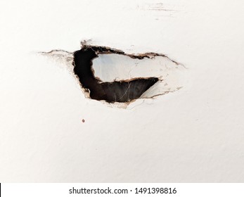 Dark Hole in the Wall on White Drywall Showing Major Damage Needing Repair in a Garage or Other Space