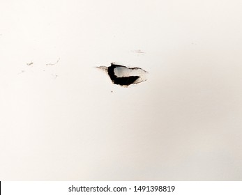 Dark Hole In The Wall On White Drywall Showing Major Damage Needing Repair In A Garage Or Other Space